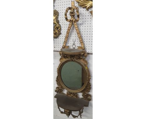 Gilt wood wall bracket with oval mirror and a shelf above and below, carved acanthus and swags and a bow surmount, mirror hei