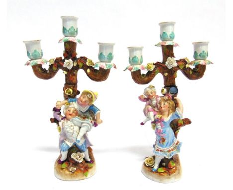 A PAIR OF CONTINENTAL FIGURAL THREE LIGHT CANDLESTICK,  modelled as children playing against tree trunks, 29.5cm high, impres