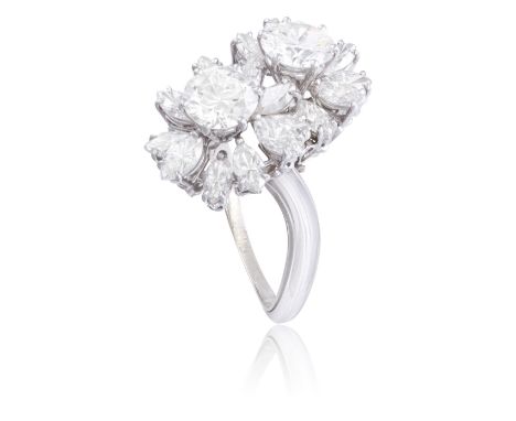 A DIAMOND CROSS-OVER RINGDesigned as two flowerheads, composed of two round brilliant-cut diamonds within a surround of marqu