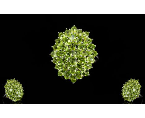 Peridot Large Oval Cluster Ring, a large cluster of oval and round cuts of peridot totalling 6.5cts, set over a low cage gall