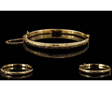 9ct Gold Bangle With Attached Safety Chain Hinged bangle, fully hallmarked for 9ct gold, the front etched with foliate scroll