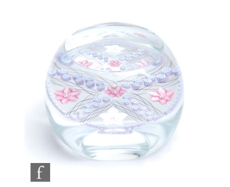 A Caithness faceted glass paperweight designed by Fiona Steel, decorated with lamp work flower heads in pink and opal space b