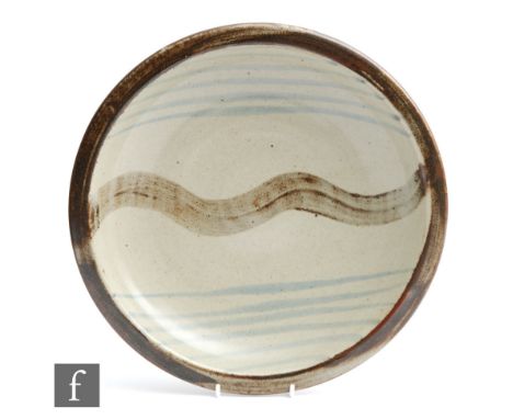 A studio pottery shallow bowl, possibly Leach Pottery St Ives, decorated with a central wavy brush stroke over the oatmeal gr