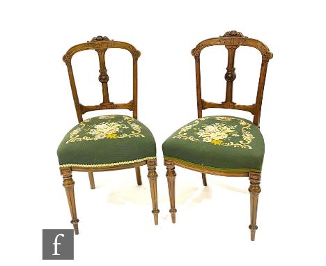 A set of four Victorian carved walnut drawing room chairs on fluted legs terminating in peg feet, upholstered in green floral