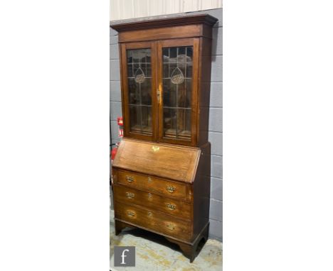A George III style oak bureau bookcase enclosed by a pair of coloured leaded light doors over a fitted interior and three fur