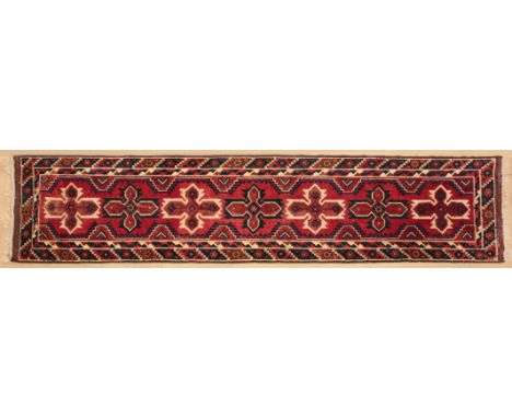 A MIDDLE EASTERN CARPET RUNNERwith red background and cross motifs, within conforming borders, 290cm long X 72cm wide