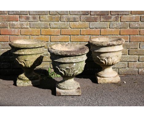 THREE SMALL RECONSTITUTED STONE URNSwith egg and dart rims and acanthus leaf bodies, terminating on square bases, 45cm high x