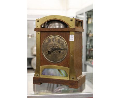 An oak cased Arts &amp; Crafts mantle clock made for Liberty's, with a domed top case, exposed bell, embossed metal dial and 