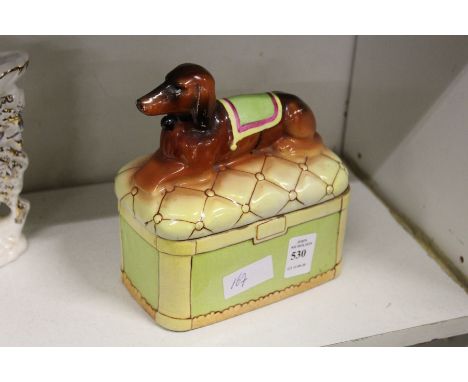 A pottery box and cover modelled as a dog seated on a cushion.