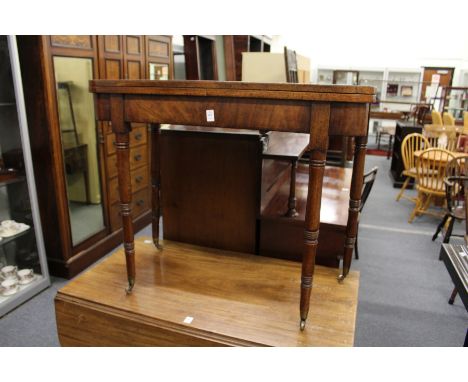 A George III mahogany D-shaped foldover card table on turned legs with brass castors.