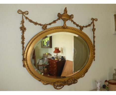 LATE 19TH CENTURY OVAL MIRROR WITH GILTWOOD FRAMED DECORATED WITH SWAGS AND A GRECIAN URN, 91 X 83 cm OVERALL