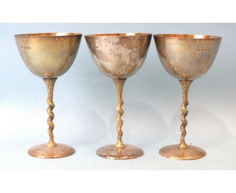 Three Stuart Devlin parcel-gilt silver goblets, each with gilt bowl and beaten exterior, on gilt twisted stems and beaten cir