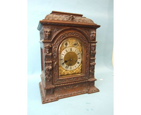 An Edwardian carved oak bracket clock, the arched gilt brass dial with silvered chapter ring, slow/fast and chime/silent dial