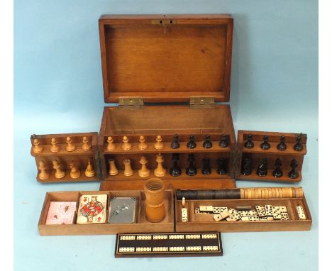 An oak games compendium, containing a carved wood chess set, dominoes, cribbage board, draughts, six dice, a turned wood shak