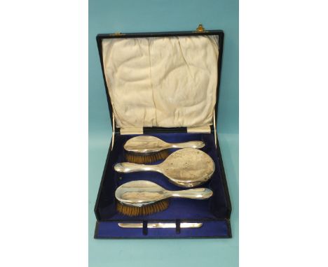 A cased silver dressing table set, comprising mirror, two brushes and a comb mount, all monogrammed, Birmingham 1924. 