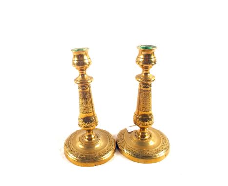 A pair of early 19th Century French seamed Brass candlesticks with engine milled decoration and circular bases, 7 1/4" high