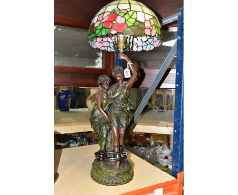 A TIFFANY STYLE LAMP, lamp base is of a young Grecian couple, the male figure is holding the shade aloft, the glass shade is 