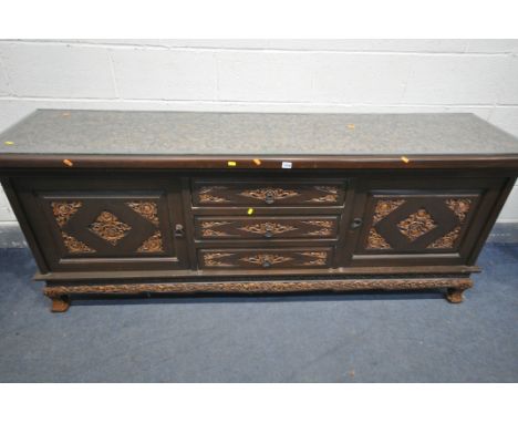 A 20TH CENTURY THAI ORIENTAL HEAVILY CARVED STAINED TEAK SIDEBOARD, the recessed top with a repeating pattern, with three dra