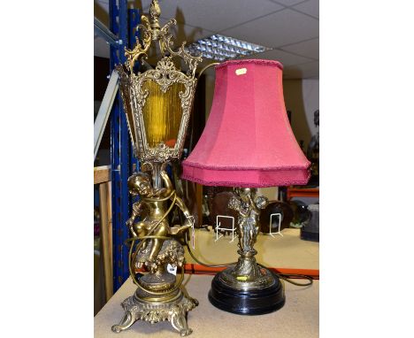 TWO BRASS TABLE LAMPS, one with a dark red shade, height 58cm to top of shade, a brass stand with two Putti holding the light