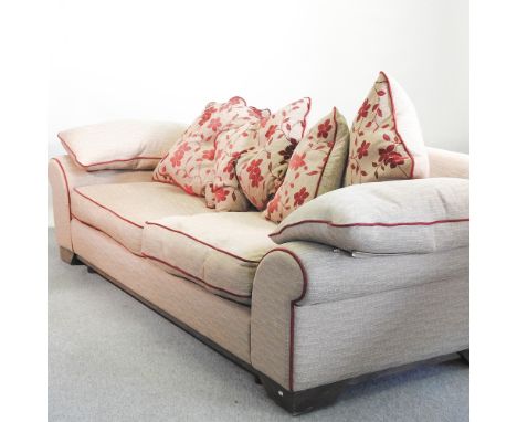 A beige upholstered sofa, 254cm, with loose cushions, together with a set of three long curtains, 212cm x 135cm, and another 