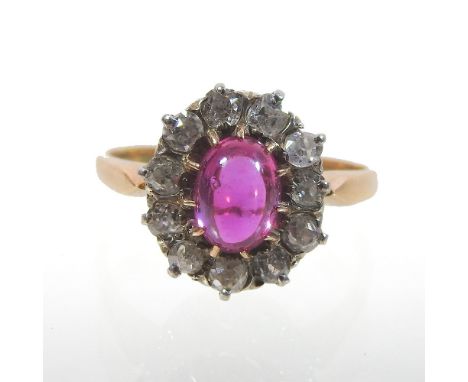 An unmarked ruby and diamond cluster ring, of flower head design, with a central cabochon ruby, within eleven diamonds, size 