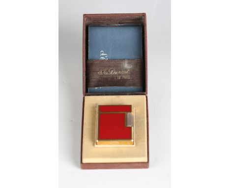 An S.T. Dupont Paris gilt metal and red enamel pocket lighter, detailed 'B5AG53', length 4.6cm, cased, with booklet.Buyer’s P
