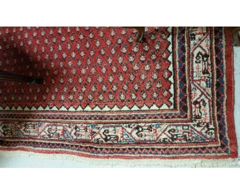 A Modern Middle Eastern Carpet; decorated with boteh (paisley) pattern on a red ground within multi borders.