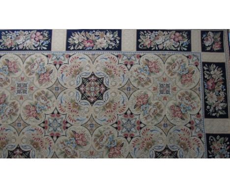 An Aubusson Type Needlepoint Carpet with stylised floral medallions and running borders, on a beige ground.