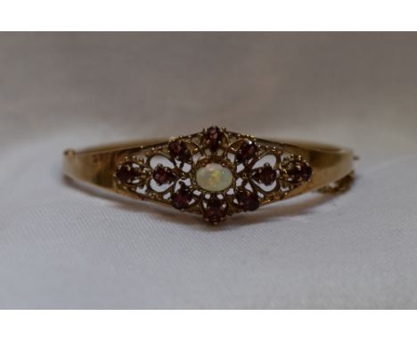 A 9ct gold hinged bangle having an opal and tourmaline set open panel and concealed clasp