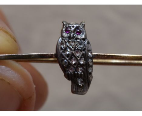 An owl brooch having diamond chip decoration and ruby cabouchon eyes on a rose metal bar stamped 9ct