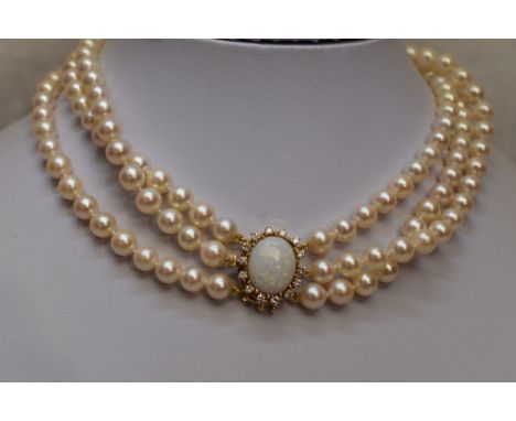 A triple string of cultured pearls of even form having a large oval yellow metal box clasp stamped 585 set with a central opa