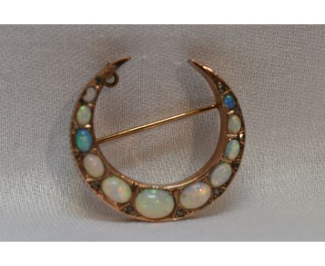 A graduated opal set crescent brooch having diamond chip decoration on a yellow metal gallery mount, no marks tested as 15ct 