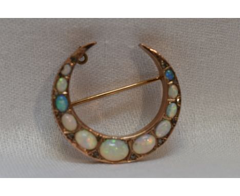 A graduated opal set crescent brooch having diamond chip decoration on a yellow metal gallery mount, no marks tested as 15ct 