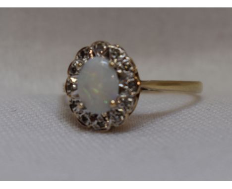 A lady's dress ring having an oval opal and diamond chip cluster in an illusionary mount on a 9ct gold loop, size N/O&nbsp; w