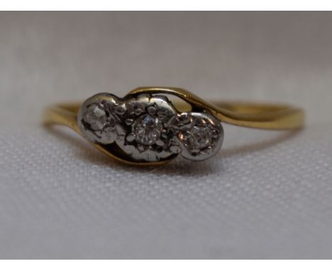 A lady's dress ring having a trilogy of diamond chips in an illusionary mount to cross over shoulders on a yellow metal loop 