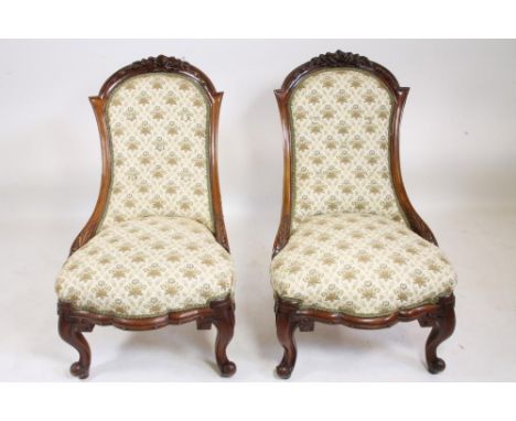A PAIR OF VICTORIAN WALNUT FRAMED NURSING CHAIRS of Grecian form button upholstered in cream and pale green floral weave, the