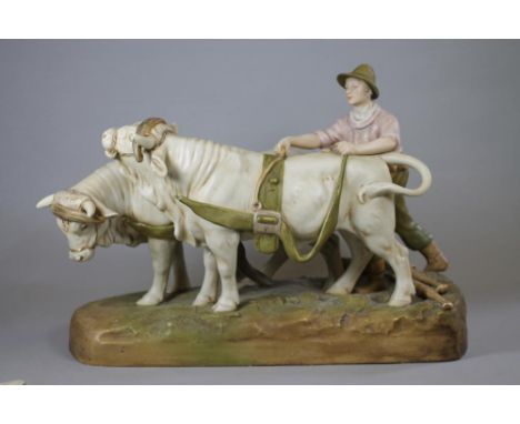 A ROYAL DUX BISQUE PORCELAIN FIGURE, early 20th century, modelled as a young plough boy harnessing a pair of bulls, the hames