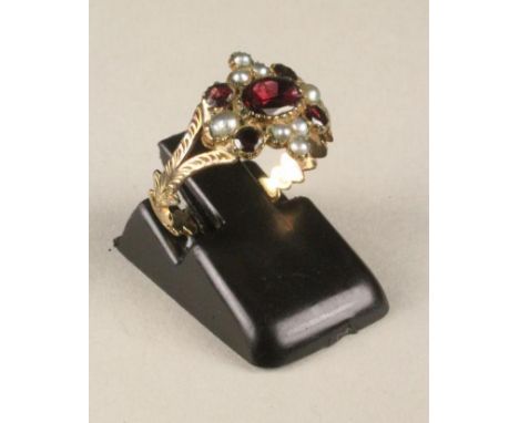 A GEORGIAN RING, the flat cut ruby in a rub-over setting in a quatrefoil panel further set with four small stones and seed pe