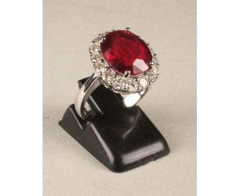 A RUBY AND DIAMOND CLUSTER RING, the oval facet cut ruby of approximately 7cts, claw set to a border pave set with sixteen sm