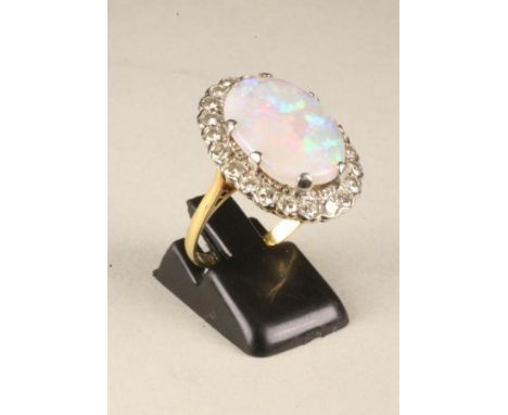 AN OPAL AND DIAMOND DRESS RING, the oval cabochon polished opal claw set to a border of twenty two small brilliant cut diamon