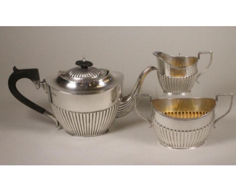 A SILVER THREE PIECE TEA SERVICE, makers Barker Bros., Chester 1911, of semi fluted oval form, comprising teapot, the hinged 