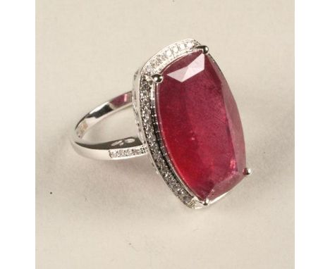 A RUBY AND DIAMOND COCKTAIL RING, the cushion cut ruby of approximately 10.35cts, claw set to a border pave set with numerous