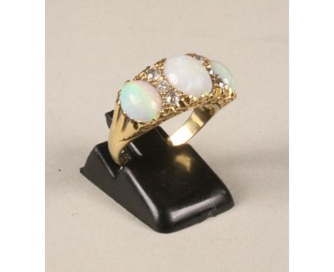 AN OPAL AND DIAMOND RING, the three oval cabochon polished stones set with an oval panel millegrain set with six small round 