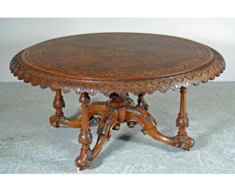 A VICTORIAN WALNUT CENTRE TABLE, the circular banded and figured top with flower carved scalloped edge, central inlaid geomet