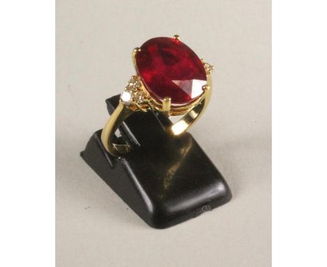 A RUBY RING, the oval facet cut stone of approximately 7cts, claw set to triangular shoulders each set with three small round