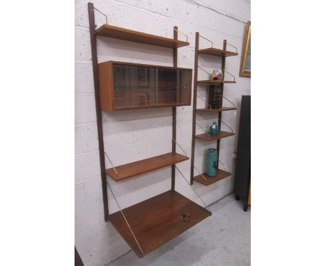 POUL CADOVIUS, A Danish teak "Royal Shelving System" suspended from wooden uprights by brass hangers, 69 1/4" high, and compr