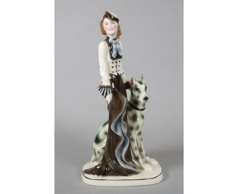 AN ART DECO KATZHUTTE EARTHENWARE FIGURE modelled as a stylish young lady wearing a hat and blue trimmed cream and brown long