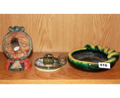 A 1947 carved wooden Black Forest amusing head of an old lady with a ceramic chamber stick and ceramic bowl, lady H. 15cm.