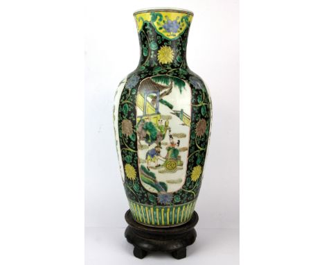 A Chinese 19th/ early 20th Century famille noire decorated porcelain vase and carved wooden stand, vase H. 41cm.