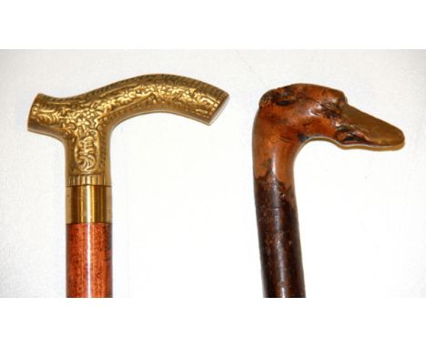 An interesting carved greyhound head walking stick and a modern brass handled walking stick containing a glass phial.